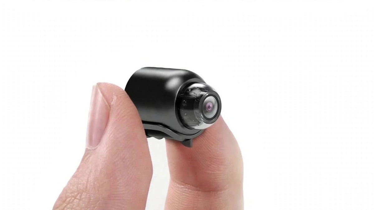 Une mini caméra Wi-Fi tenue entre deux doigts pour en montrer la taille